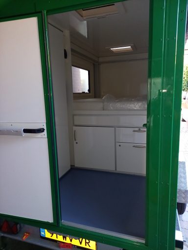 Binnenkant caravan op maat Groene trailer met een open deur en een witte binneninrichting wat dient als caravan.