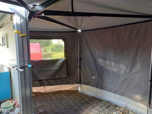 Binnenkant tent caravan op maat Een lege voortent met een grijze wand en een geopend venster.