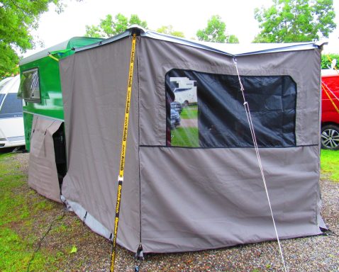 Tent en afdekhoes fietsen Een grijze tent bevestigd aan de luifel van een groene MaatHout caravan op maat, beeld vanaf de achterkant van de caravan.