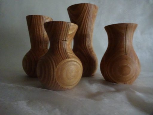 Houten vazen Vier houten vazen met een strakke, organische vorm en een lichte houtkleur.