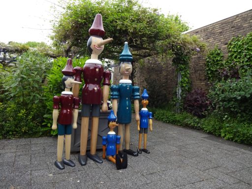 Grote houten kleurrijke Pinokkio's Een groep houten Pinokkio-figuren in diverse maten en kleuren.