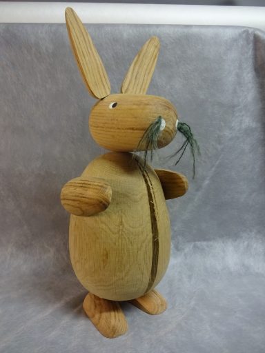 Houten Paashaas Houten Paashaas met lange oren en snor, staand op een grijze achtergrond.