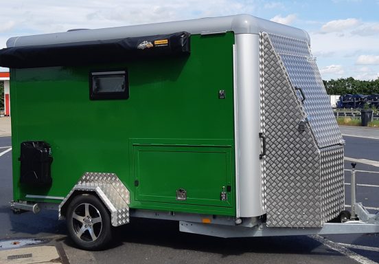 Luik buitenkeuken Groene outdoor caravan op maat gemaakt met metalen afwerking en een luik van de uitschuifbare buitenkeuken, compacte en moderne uitstraling.
