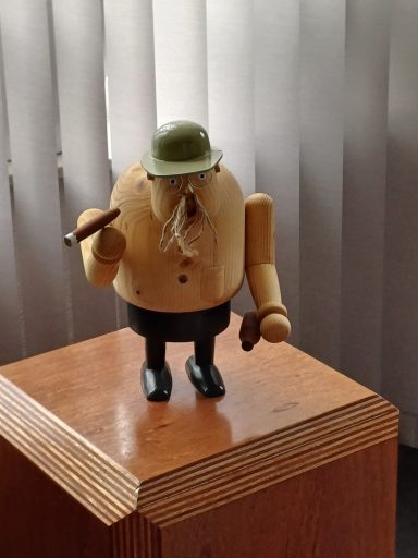 Houten oude man Houten figuur met een hoed, sigaar en twee handen, die een uitdrukking van nieuwsgierigheid heeft.