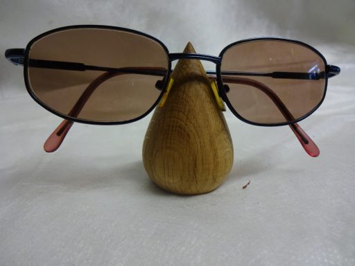 Houten brillen standaard Een zonnebril leunt op een houten brillen standaard in de vorm van een peer.