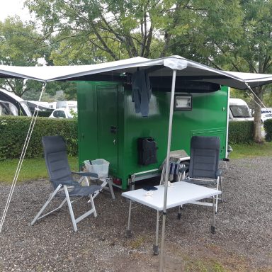 Grote luifel voor- en achterkant caravan Groene caravan met uitklapbare luifel en uitschuifbare buitenkeuken met veel bergruimte en een tuinstel onder de luifel.