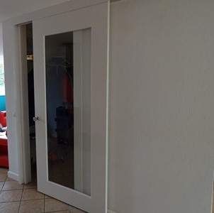 Witte houten schuifdeur met glas Witte schuifdeur met grote glazen panelen in een lichte kamer.